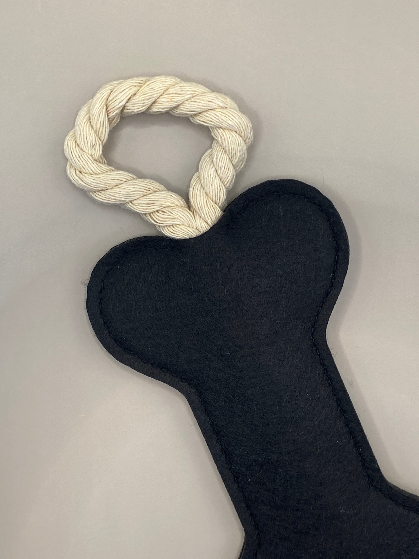 Offre à ton compagnon à quatre pattes un jouet sain et amusant ! Cet os en feutre noir avec corde intégrée est conçu pour résister aux jeux doux et au mordillage léger, tout en apportant un vrai moment de complicité.